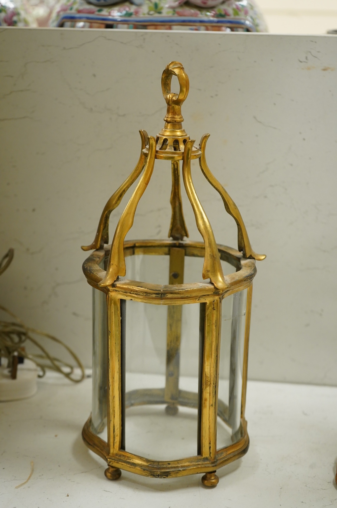 A pair of table lamps and shades, 92cm high, the lamps decorated in gold and green tones painted with birds and flowers, together with a small glass and brass hall lantern (3).